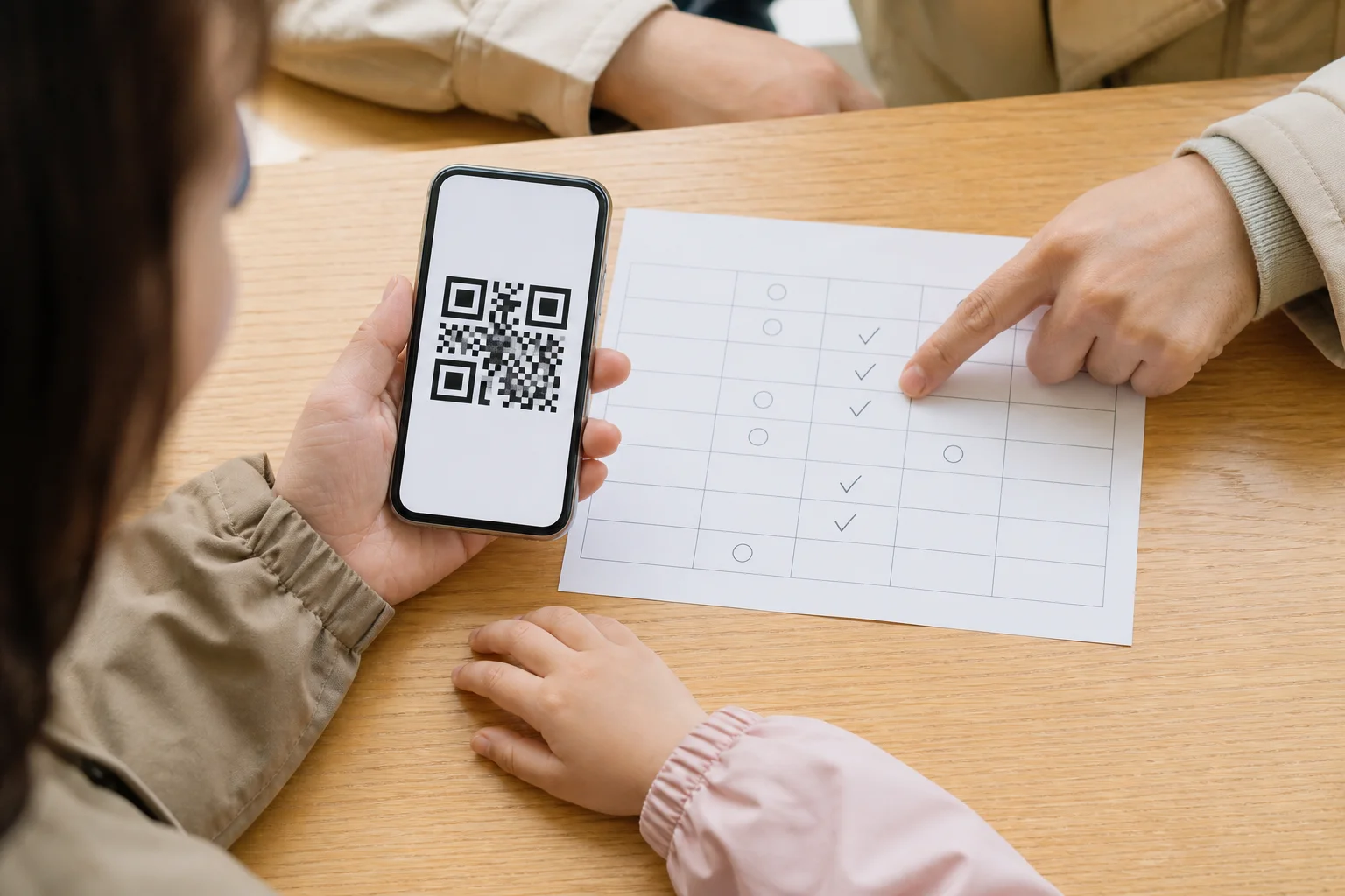 스마트폰의 입장 QR 화면과 날짜별 예약 확인표를 함께 살펴보는 가족의 손